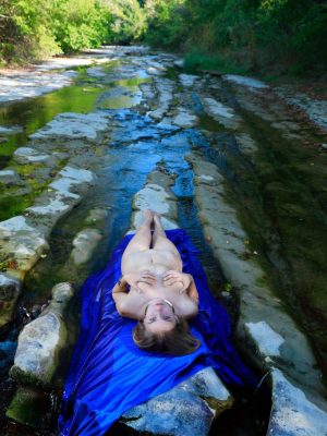 Huge tits blonde Dakota Pink is naked at the river, reclining on the rocks and paddling in the cool water